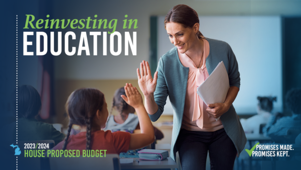 Teacher gives a student a high five in a classroom. Text at left reads "Reinvesting in education"