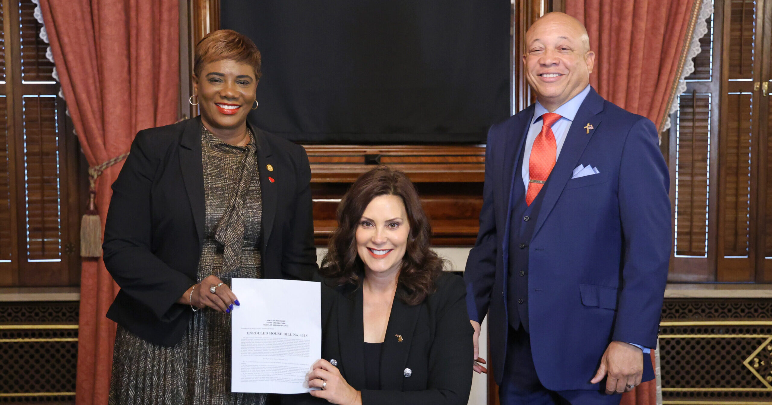 Michigan state representative Cynthia Neeley and governor Gretchen Whitmer and Flint Mayor neeley pose for a photo after a bill signing.