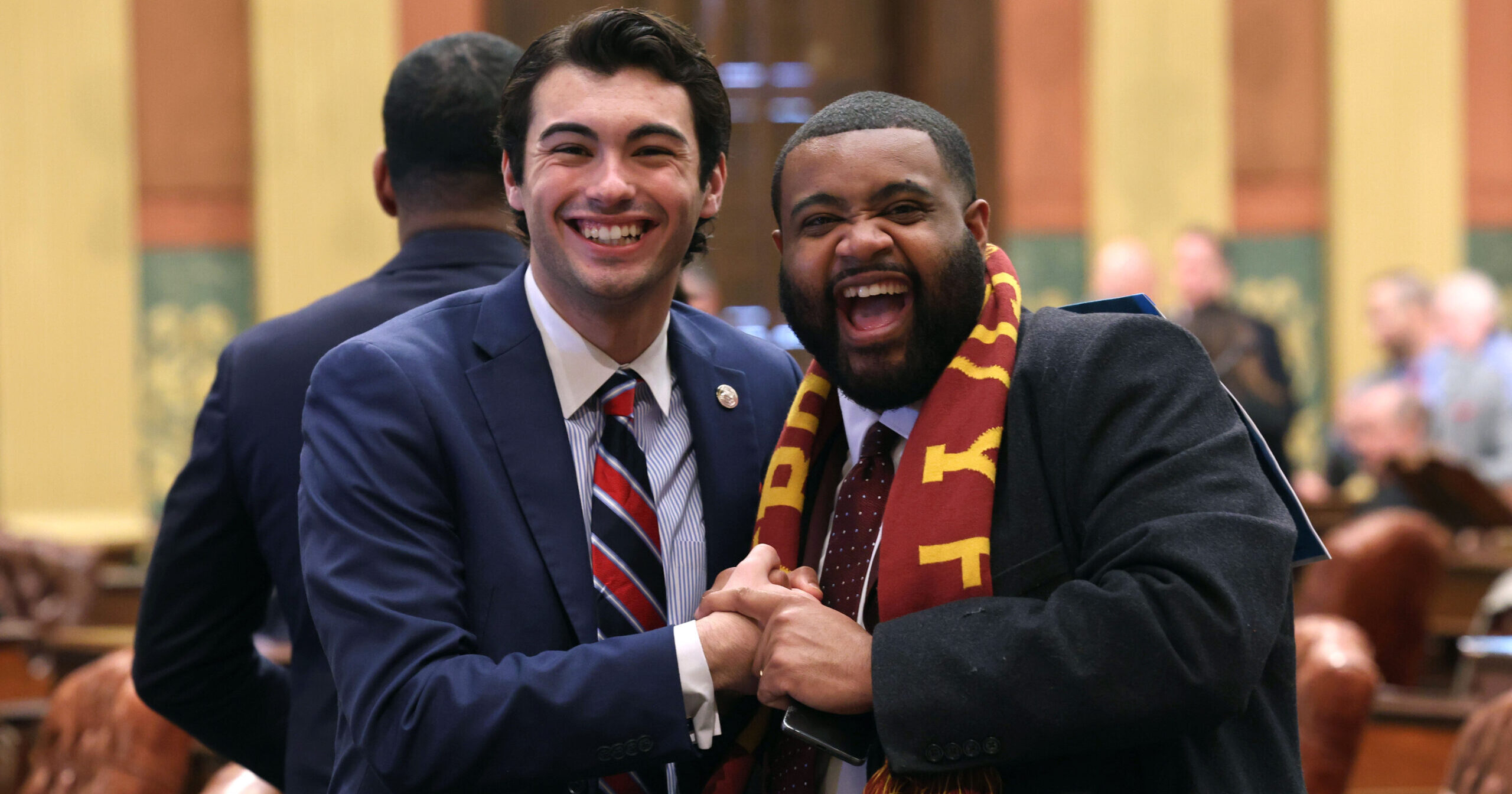 Michigan state representatives Jasper R. Martus and Donavan Mckinney stand together with big smiles.