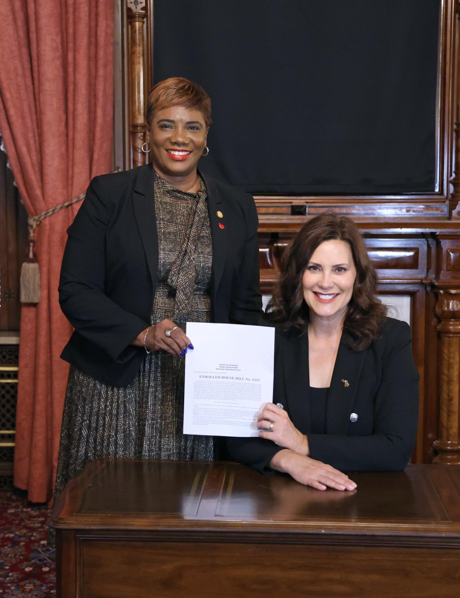 State Rep. Cynthia Neeley (D-Flint) stands next to Gov. Gretchen Whitmer after Whitmer signed House Bill 4318 into law at the Michigan State Capitol on Wednesday, Sept., 27, 2023.