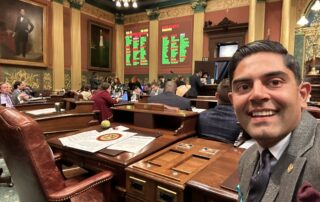 Rep. Puri takes a selfie in front of the voting board showing his vote on adding holidays to the Michigan calendar has passed on the Michigan House floor.