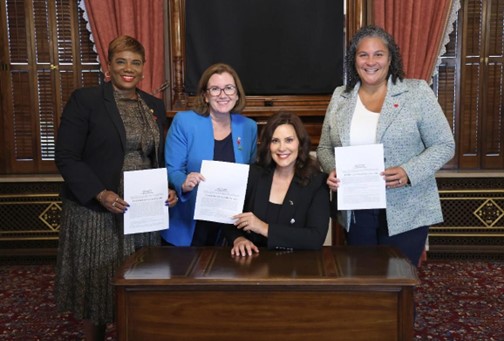 Rep. Price holds her signed bill with Gov. Whitmer. Reps. Neeley and Brabec flank with signed bills of their own. 