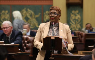 Rep. Neeley stands behind a podium on the Michigan House floor.