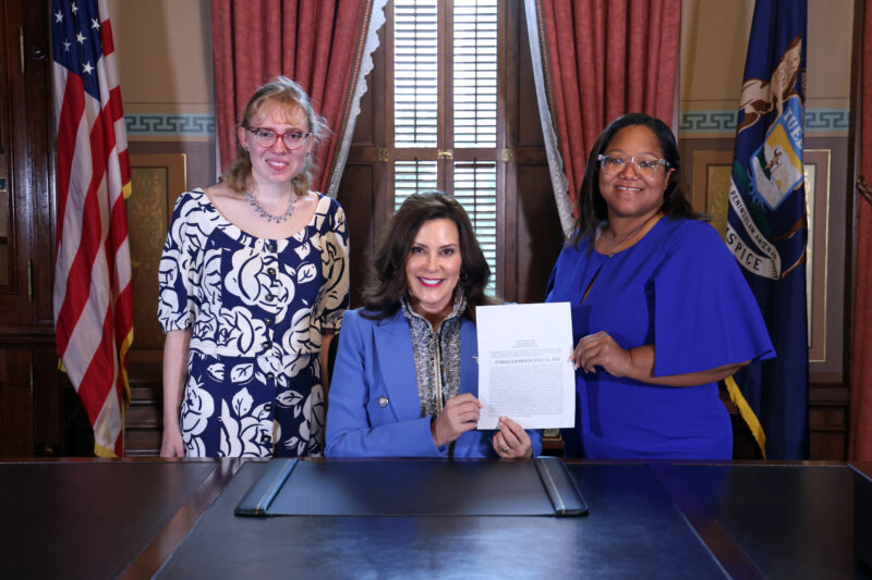 Rep. Edwards and her intern stand with Gov. Gretchen Whitmer, holding a copy of Rep. Edwards' signed bill.