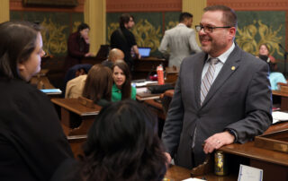 Rep. Mike McFall speaks with colleagues on the Michigan House floor.