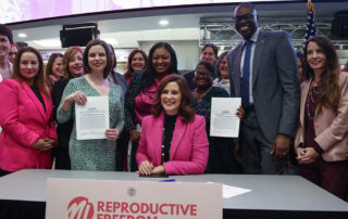 Michigan lawmakers pose with Gov. Whitmer for a photo at the Reproductive Health Act bill signing.