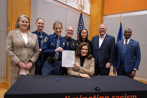 State Rep. Amos O’Neal (D-Saginaw), right, and state Sen. Sue Shink (D-Northfield Township), left, stand with Michigan State Police officers and others after Gov. Gretchen Whitmer signed legislation that bans convicted domestic abusers from owning firearms for a set number of years on Nov. 20, 2023, in Kalamazoo.