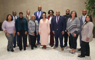 State House members of the MLBC stand in front of a natural-toned wall in Heritage Hall.