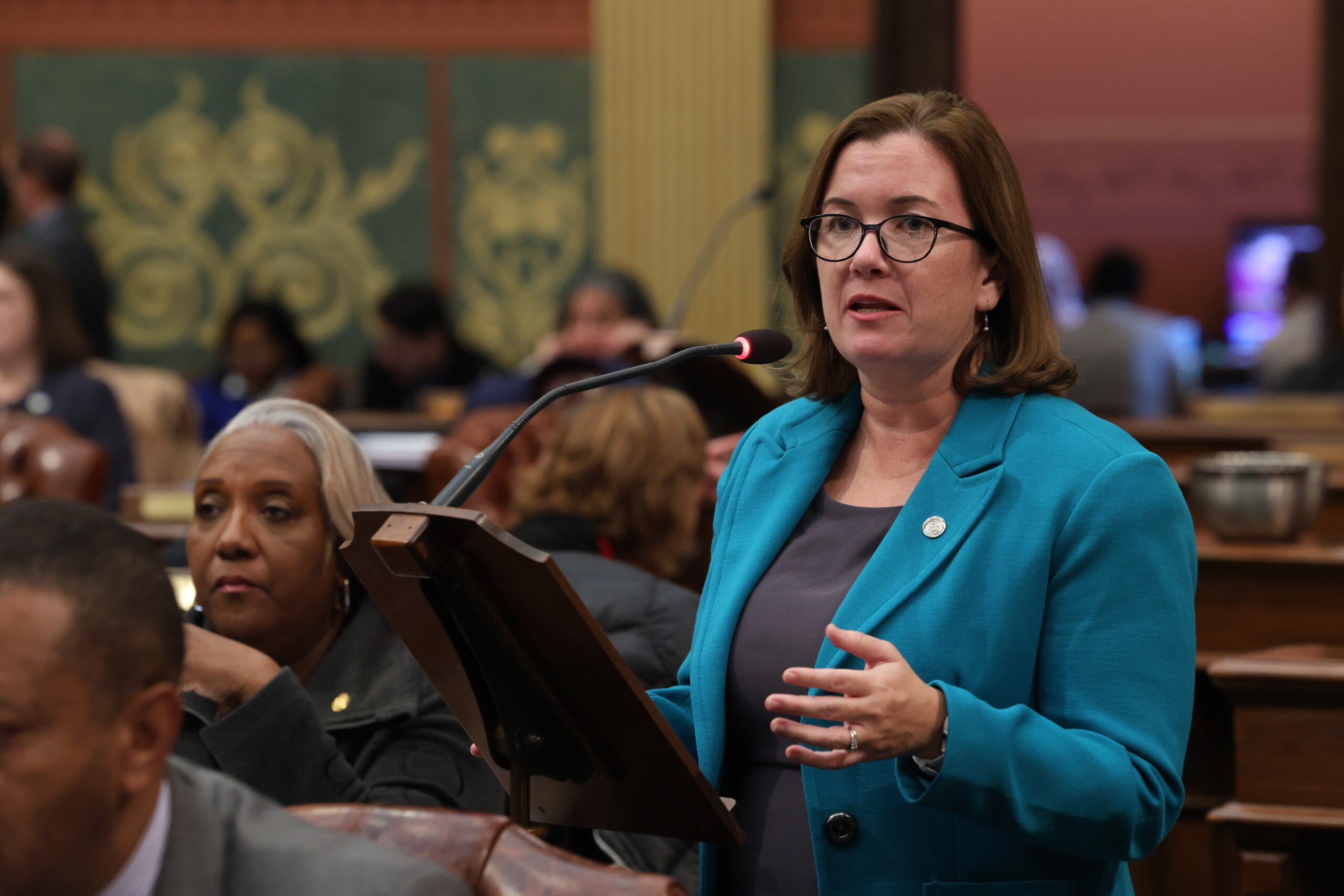 Rep. Natalie Price addresses the Michigan House from a podium on the floor.