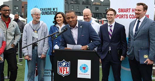 State Rep. Tyrone Carter (D-Detroit), sponsor of House Bill 5528, addresses the crowd at the NFL Draft weekend in Detroit, celebrating the signing of the AED bills by Gov. Gretchen Whitmer. Onlookers pictured include NFL player Damar Hamlin, far left, and state Rep. John Fitzgerald (D-Wyoming), far right, sponsor of House Bill 5527 in the AED package, on April 27, 2024, in Detroit.