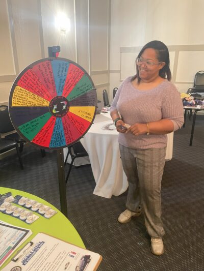 Rep. Edwards spins a prize wheel provided by one of the tablers at the Stigma Resources Fair. 