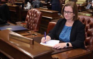 State Rep. Natalie Price writes on a copy of a bill at her desk on the House floor at the Michigan Capitol.