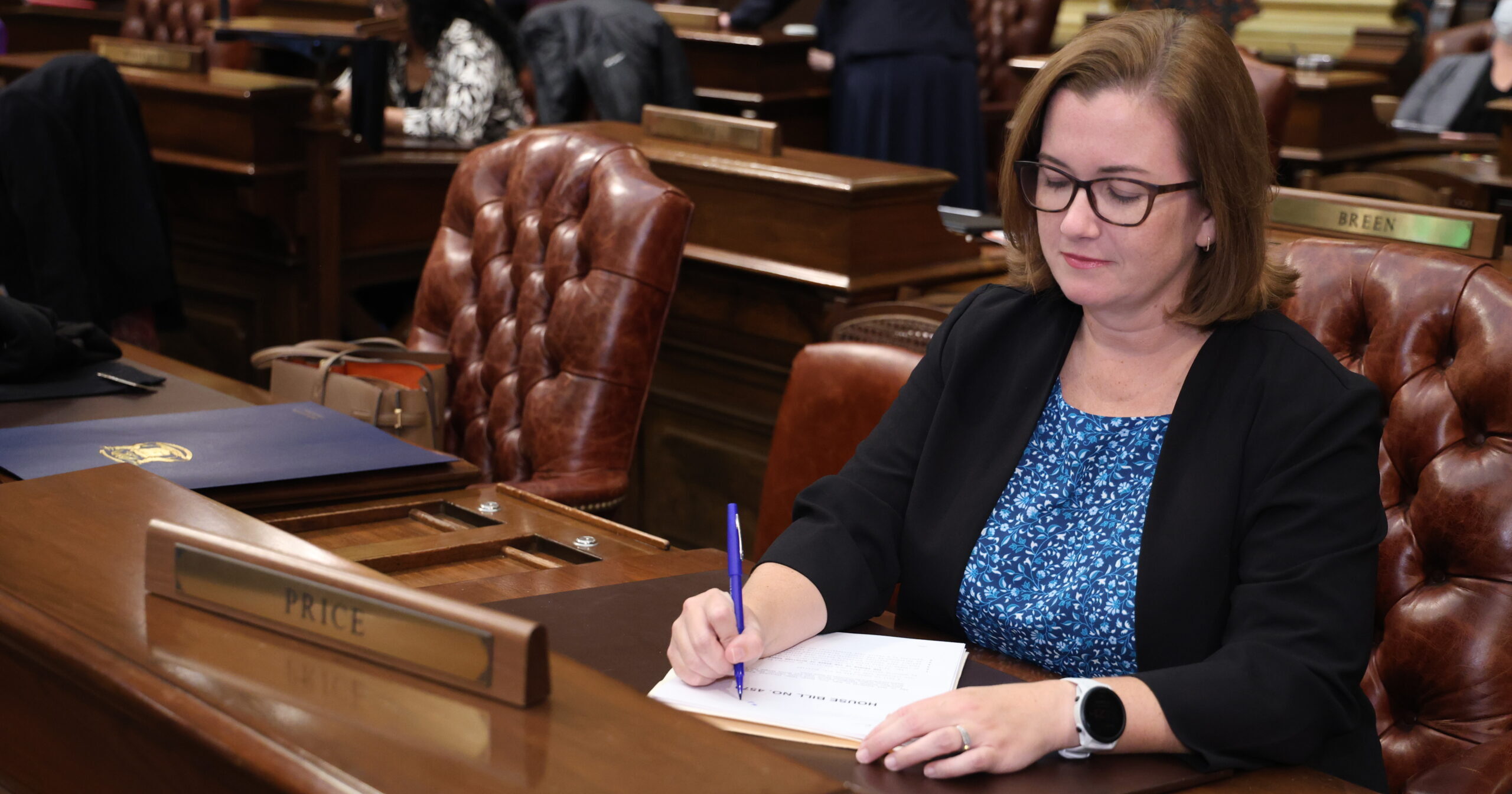 State Rep. Natalie Price writes on a copy of a bill at her desk on the House floor at the Michigan Capitol.