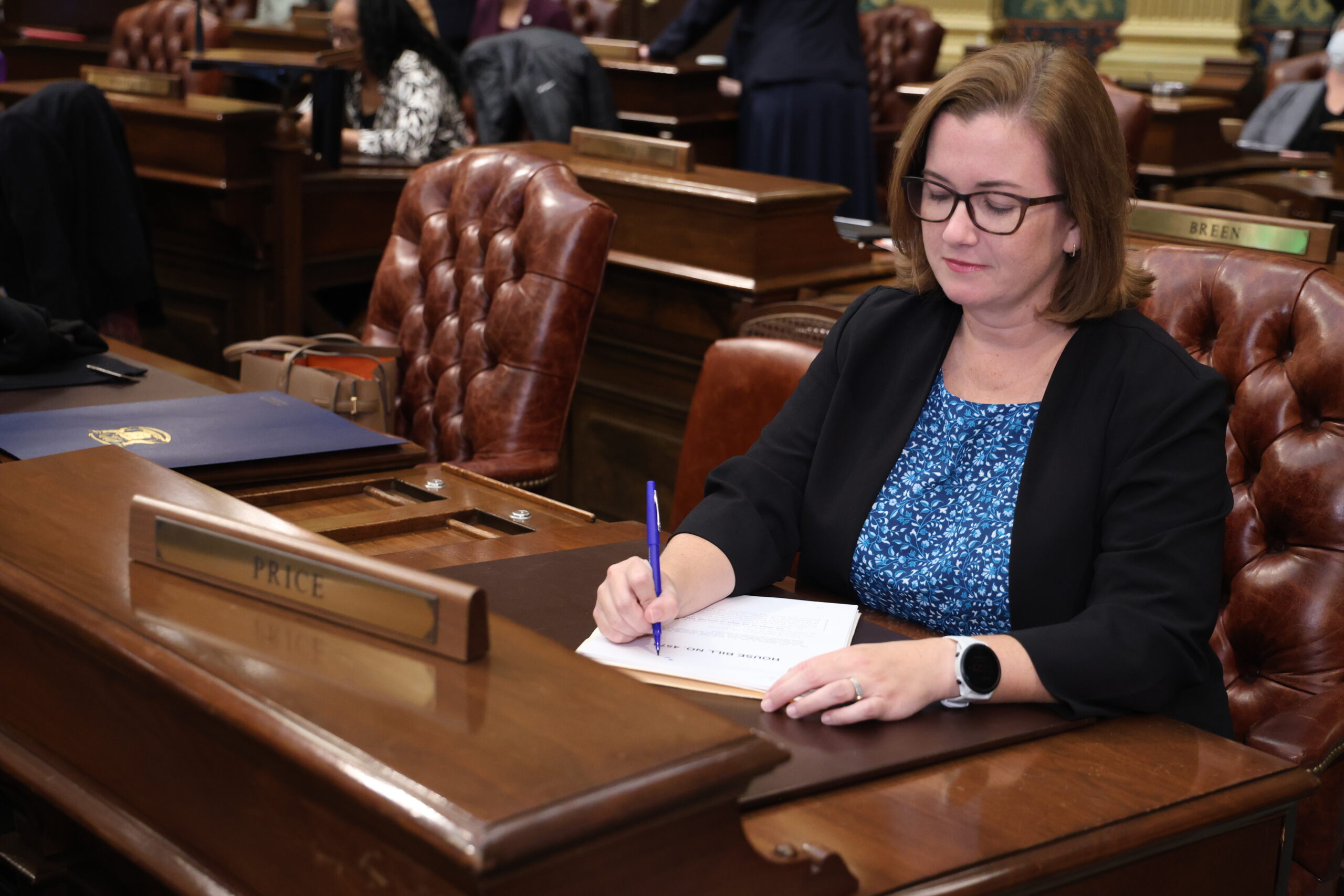 State Rep. Natalie Price writes on a copy of a bill at her desk on the House floor at the Michigan Capitol.