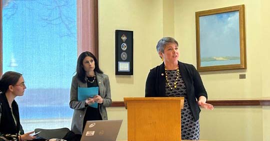 State Rep. Betsy Coffia (D-Traverse City) speaks at a Business Scams Town Hall while Attorney General Dana Nessel looks on.