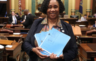 Photo of Rep. Stephanie A. Young on the House floor, March 11, 2024. Rep. Young is holding packets of legislation.