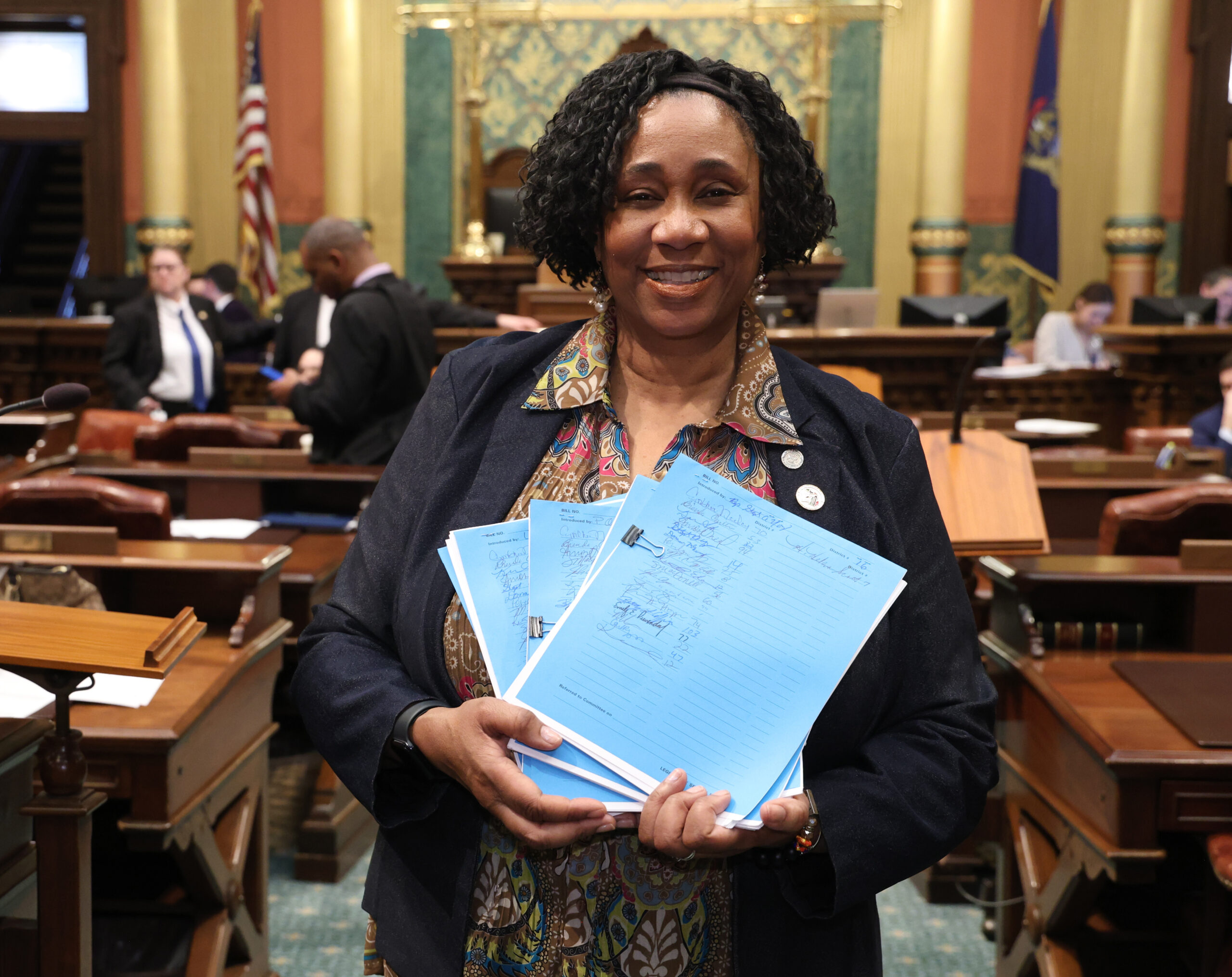 Photo of Rep. Stephanie A. Young on the House floor, March 11, 2024. Rep. Young is holding packets of legislation.