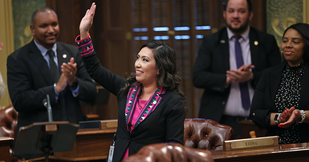 State Representative Mai Xiong waves to the gallery after delivering a speech as her colleagues applaud in the background.