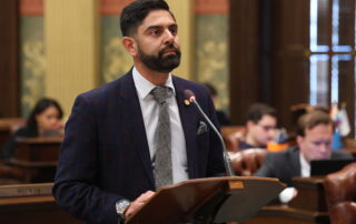 State Rep. Ranjeev Puri delivers a speech at a podium on the floor of the Michigan House.