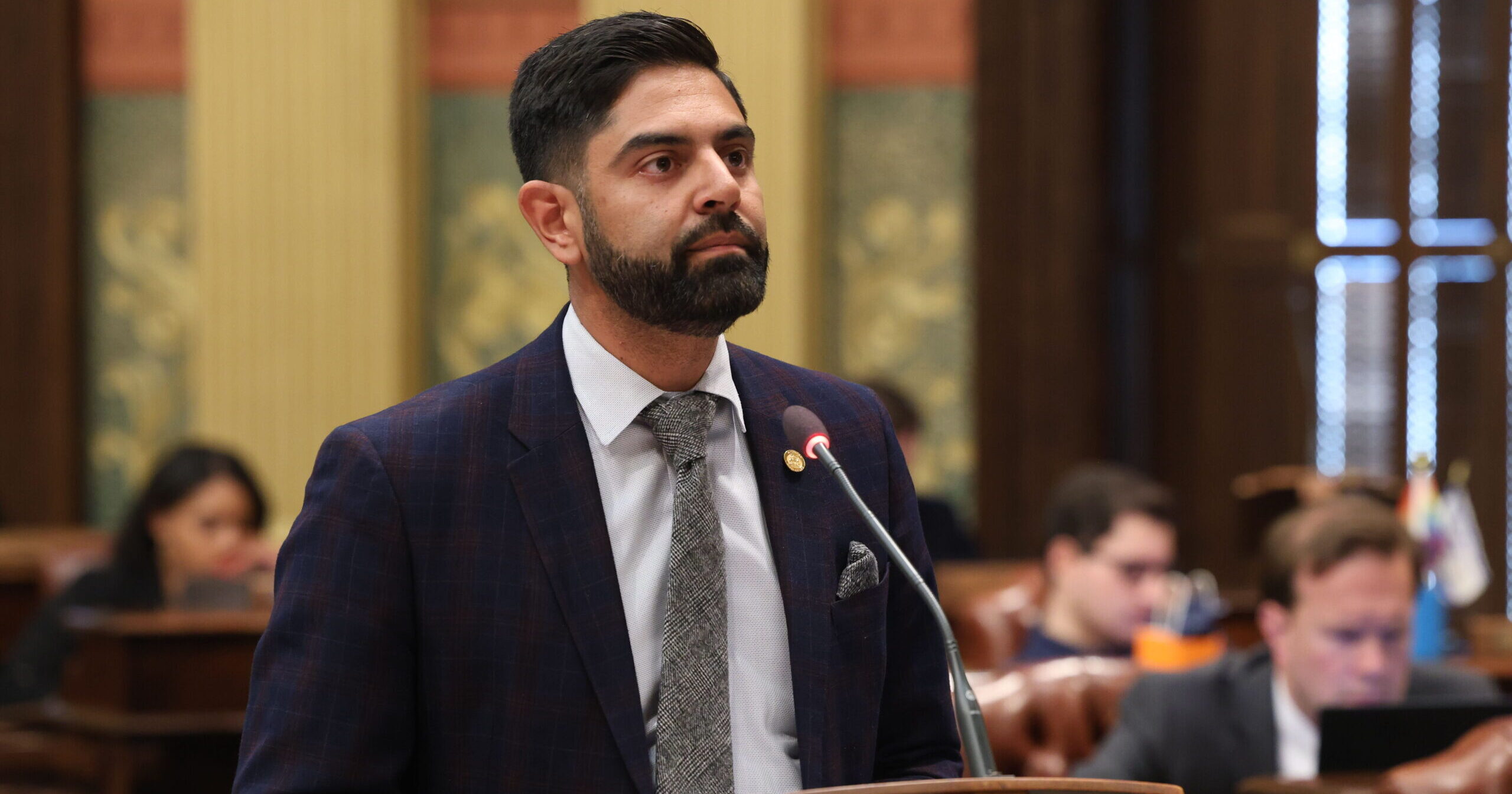 State Rep. Ranjeev Puri delivers a speech at a podium on the floor of the Michigan House.