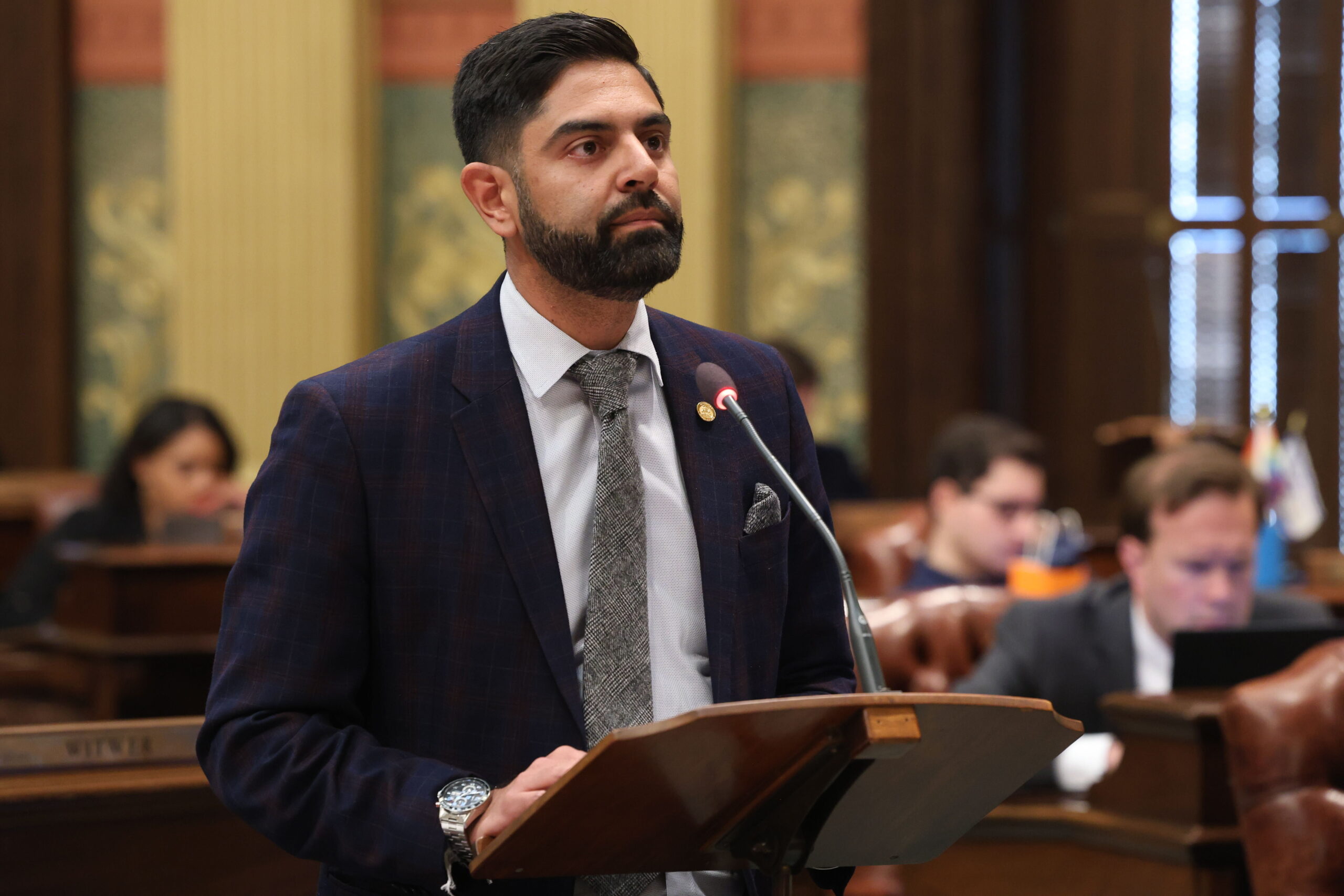 State Rep. Ranjeev Puri delivers a speech at a podium on the floor of the Michigan House.