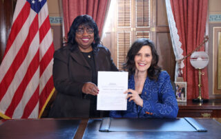 state Rep. Brenda Carter standing next to Gov. Gretchen Whitmer while they hold newly signed legislation