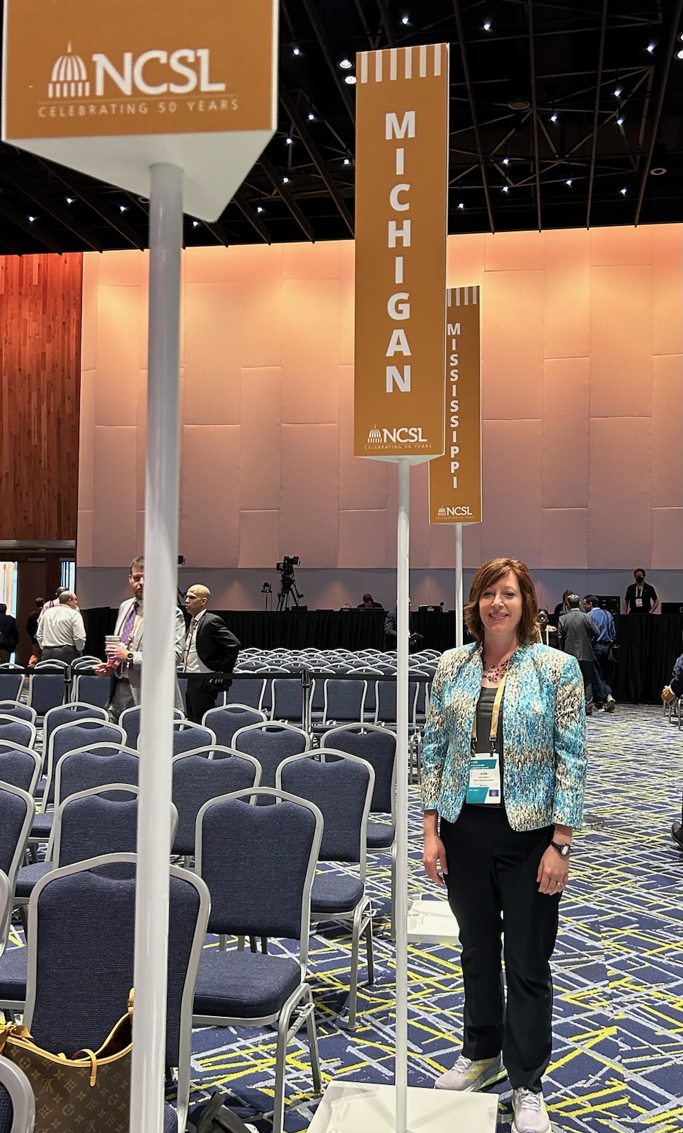 State Rep. Julie Rogers (D-Kalamazoo) stands in front of the Michigan banner at the National Conference of State Legislatures Legislative Summit.