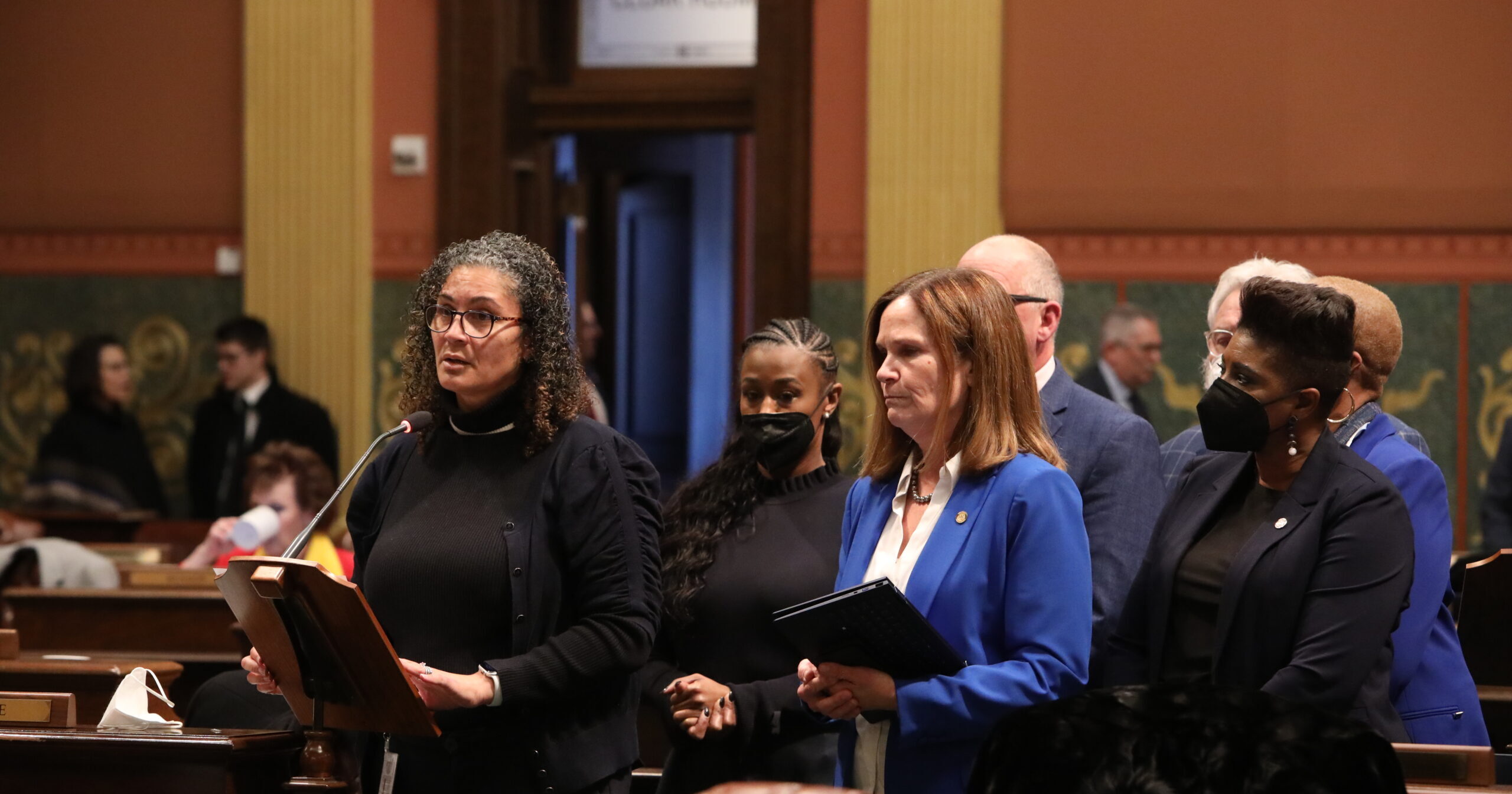 Michigan State Rep. Felicia Brabec speaks on the house floor surrounded by her colleagues.