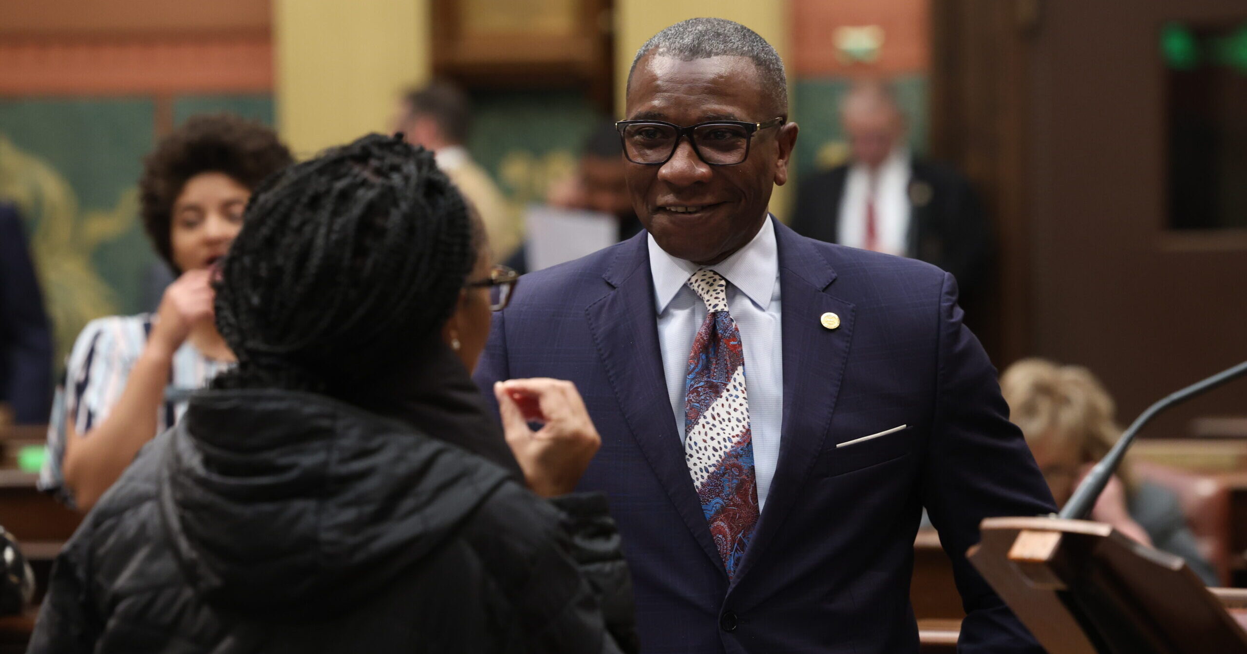 State Representative Amos O'Neal speaks to a colleague on the Michigan House Floor.