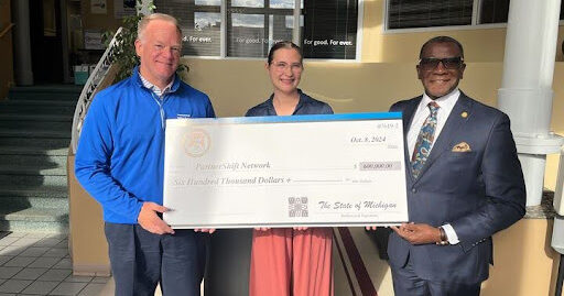 Standing together from left, PartnerShift Network, Board President Chris Vieau, Interim Executive Director Rachelle Hilliker and Michigan state Rep. Amos O’Neal (D-Saginaw) hold a check representing the secured investments for PartnerShift Network in the state budget .