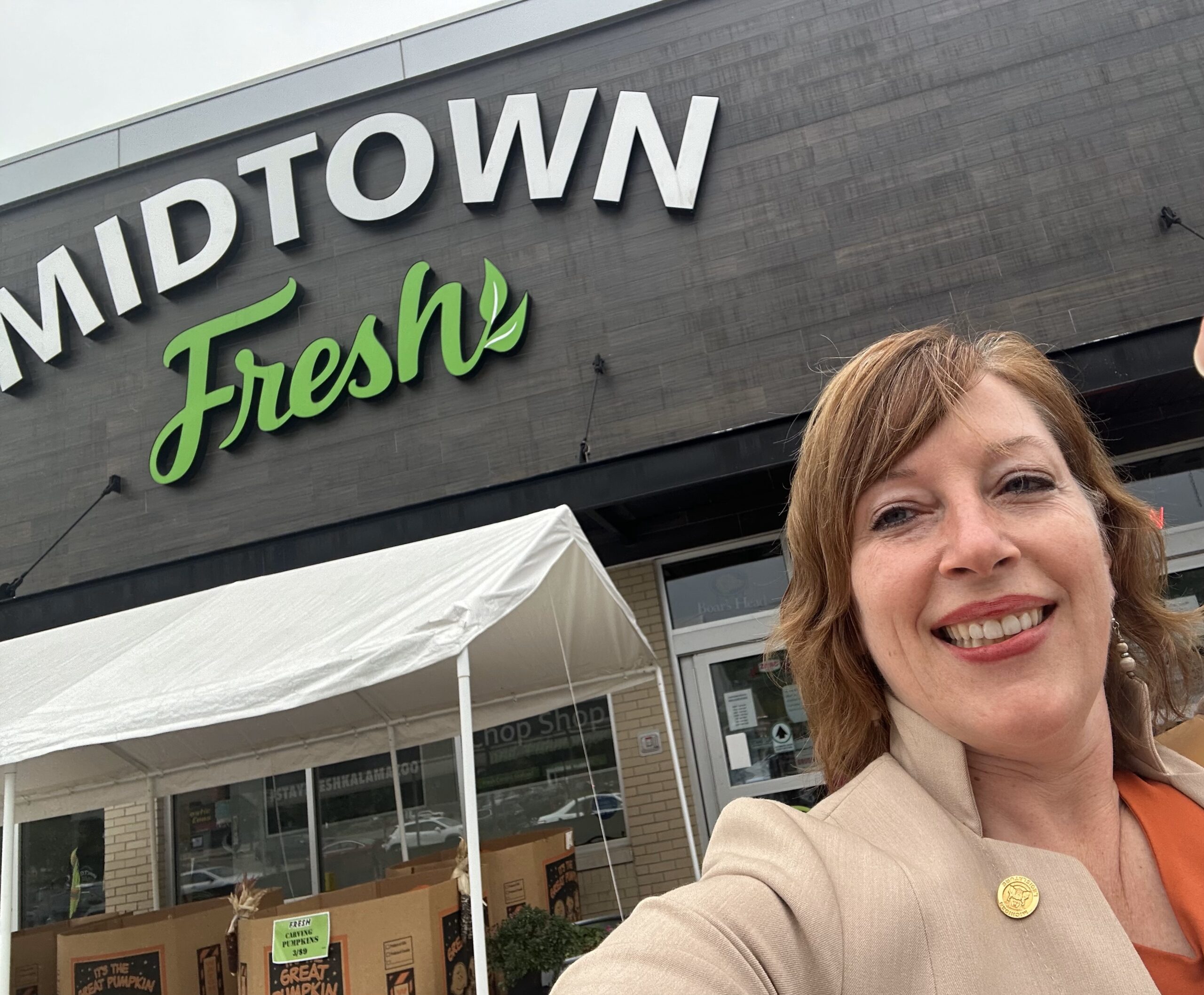 Michigan State Representative Julie Rogers stands in front of a market.