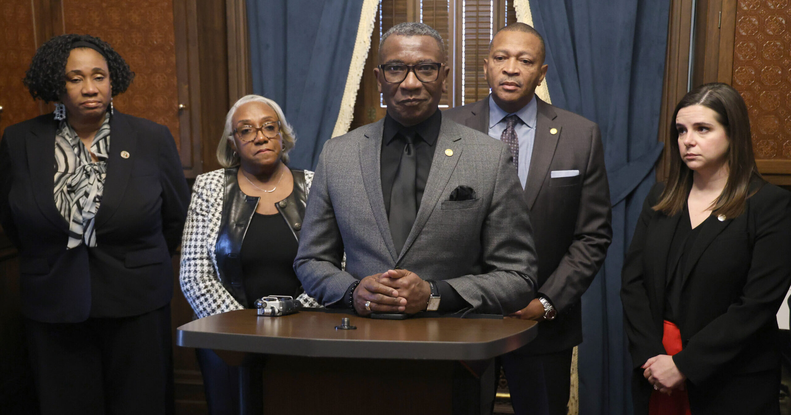 Michigan State Rep. Amos O'Neal stands surrounded by his colleagues.