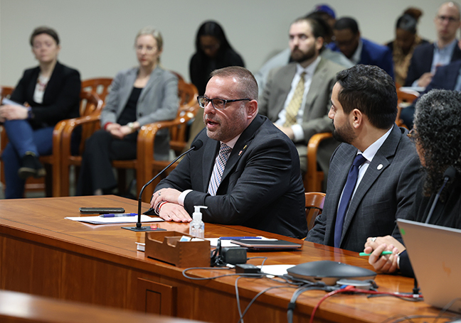 Michigan State Representative Mike McFall testifying in a House committee at the Anderson House Office Building in Lansing.