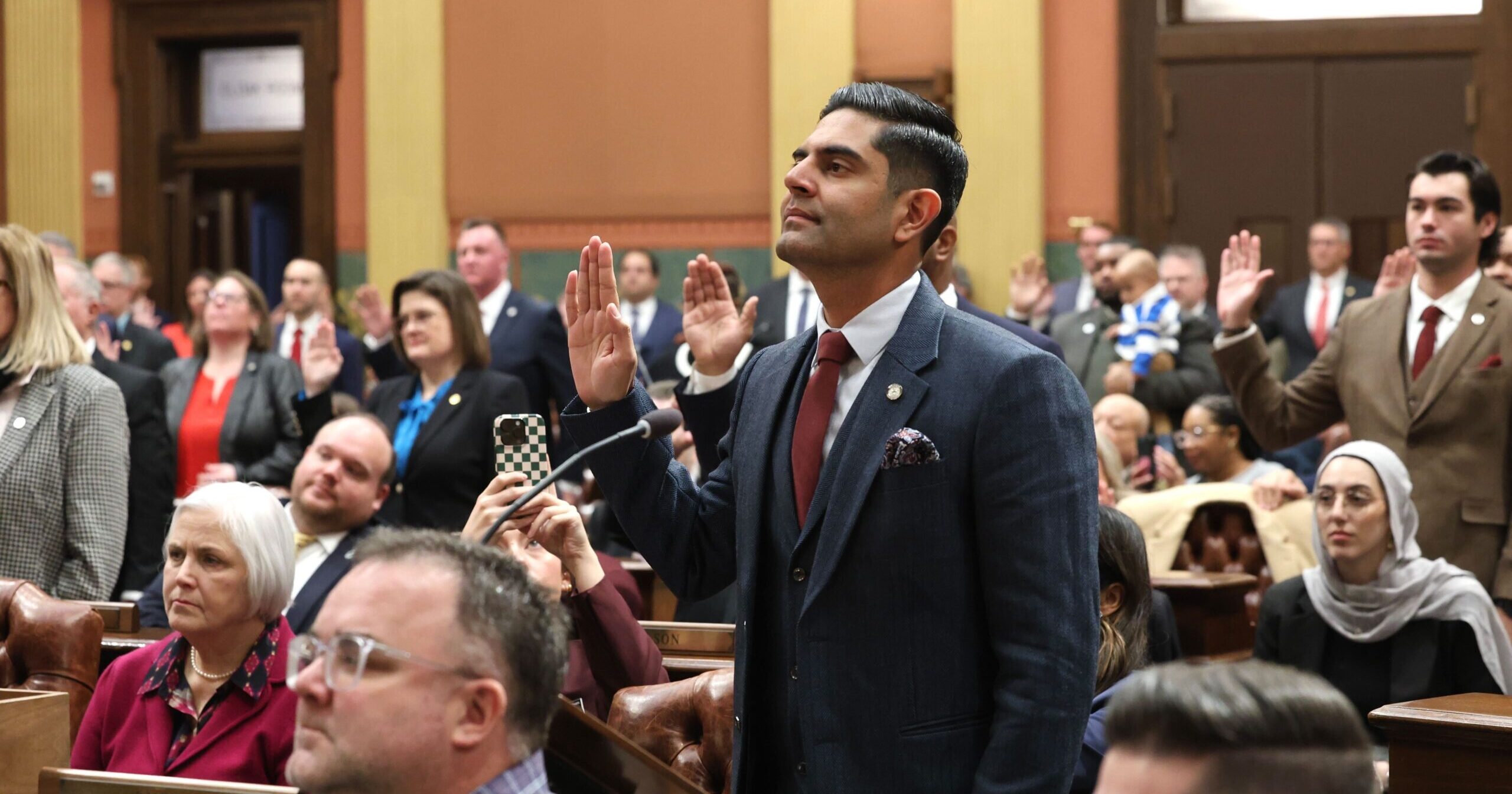 Democratic Leader Ranjeev Puri standing with his hand raised alongside members of the Democratic Caucus on the House Floor.