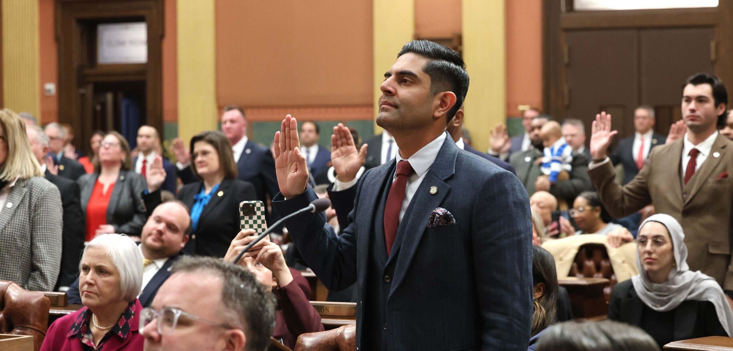 Democratic Leader Ranjeev Puri standing with his hand raised alongside members of the Democratic Caucus on the House Floor.