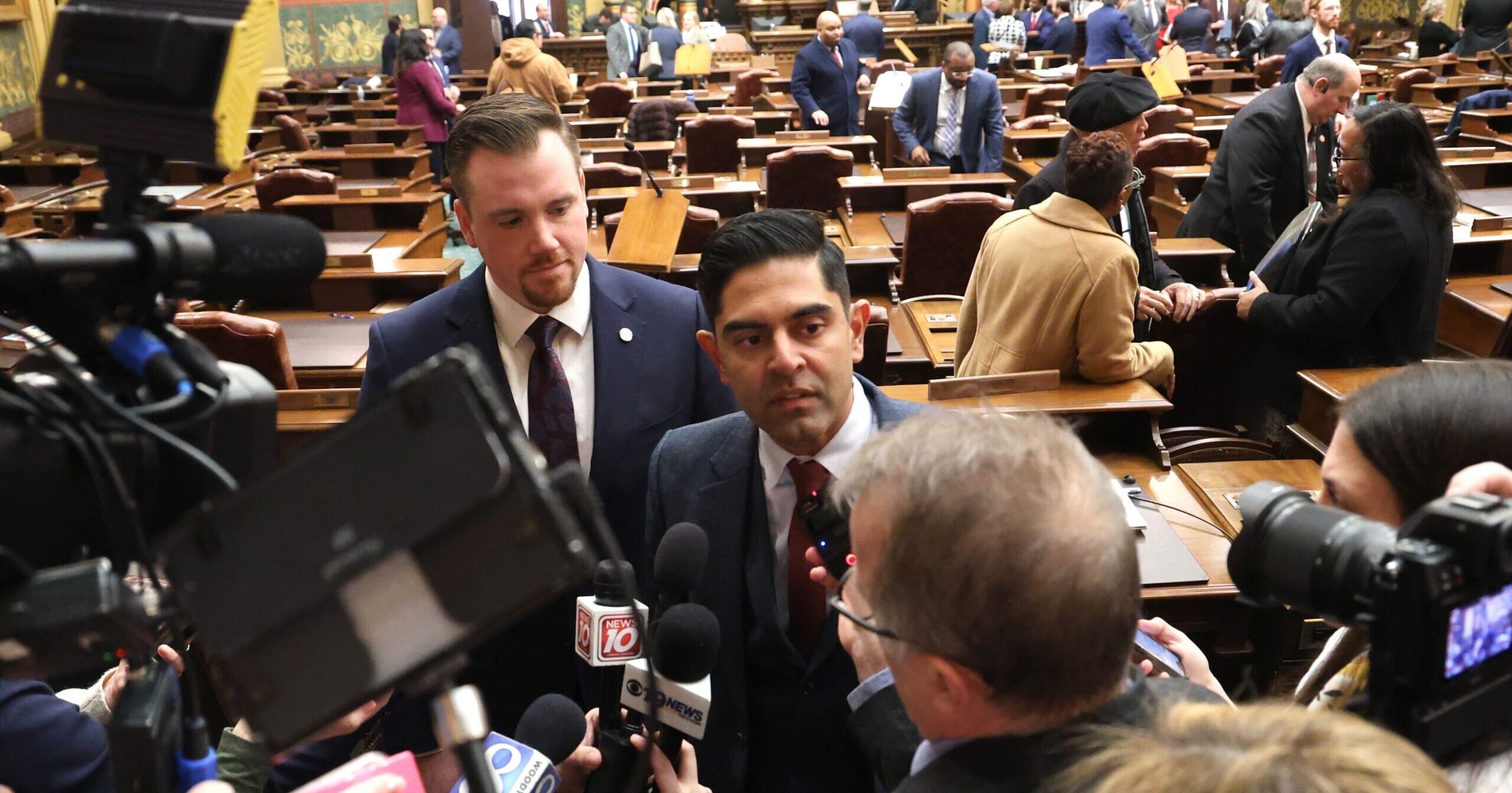 Michigan state Representatives John Fitzgerald and Ranjeev Puri surrounded by cameras and the press.