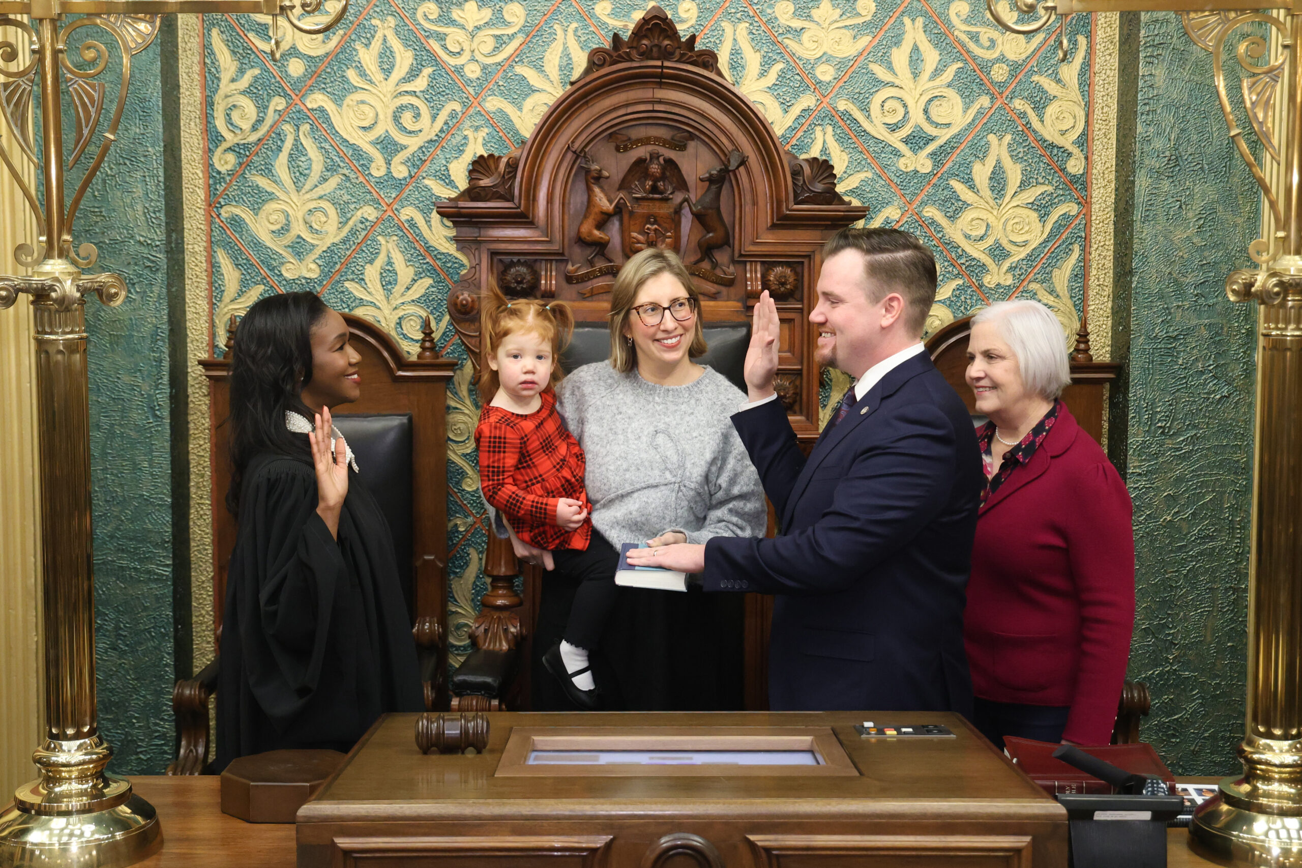 Michigan State Representative John Fitzgerald standing with his family while being sworn into the 103rd Legislature by Michigan Supreme Court Justice Kyra Harris Bolden.