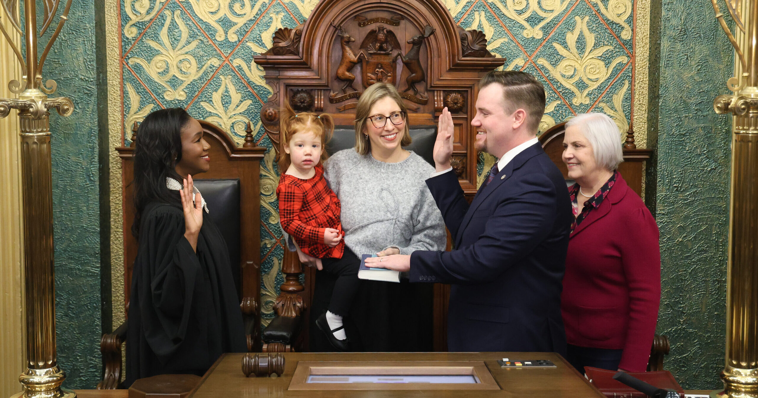 Michigan State Representative John Fitzgerald standing with guests while being ceremoniously sworn into the 103rd Legislature by Michigan Supreme Court Justice Kyra Harris Bolden.