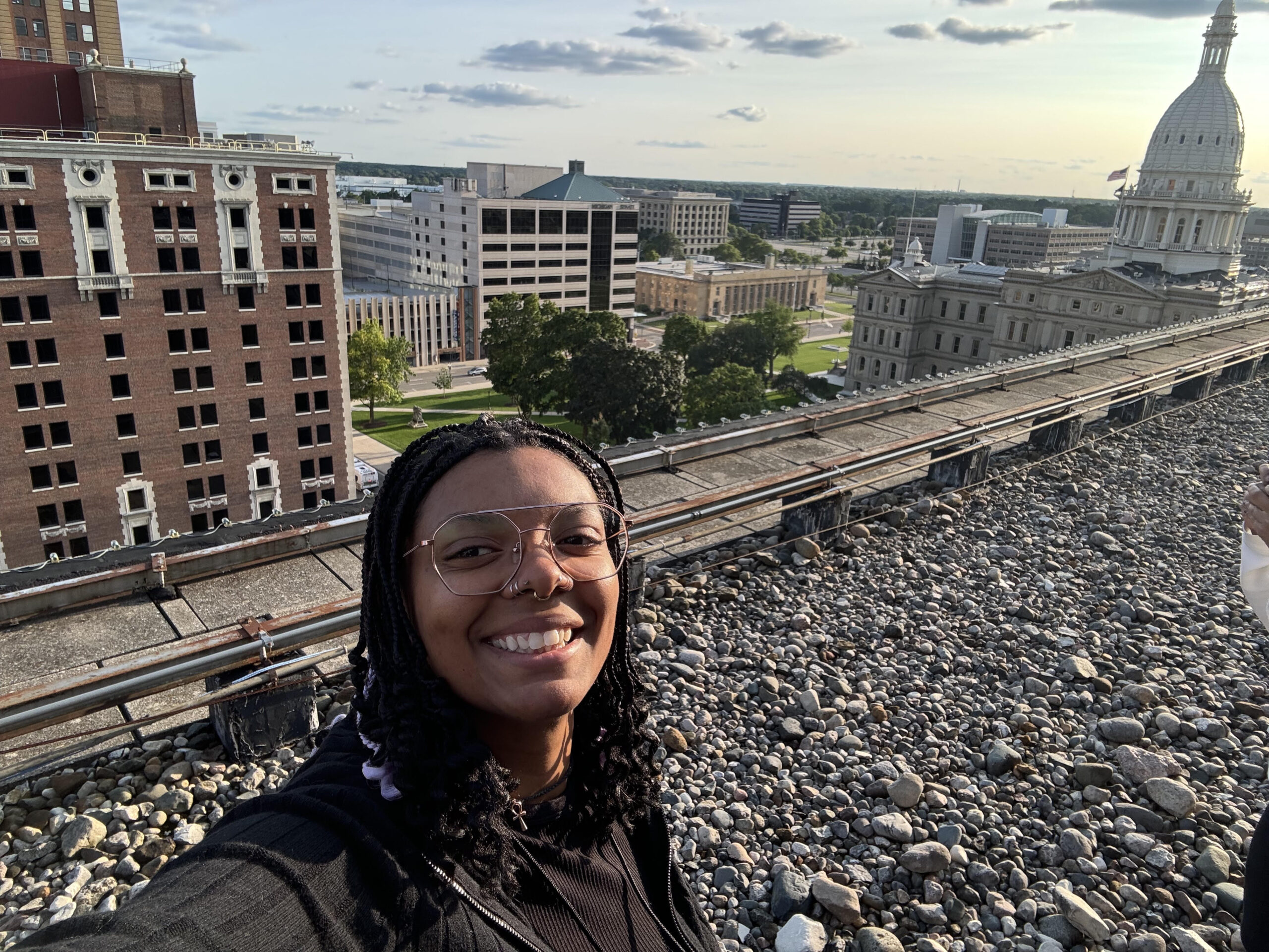 A photo of Khadja Erikson on a rooftop with the Michigan State Capitol Building in the background.