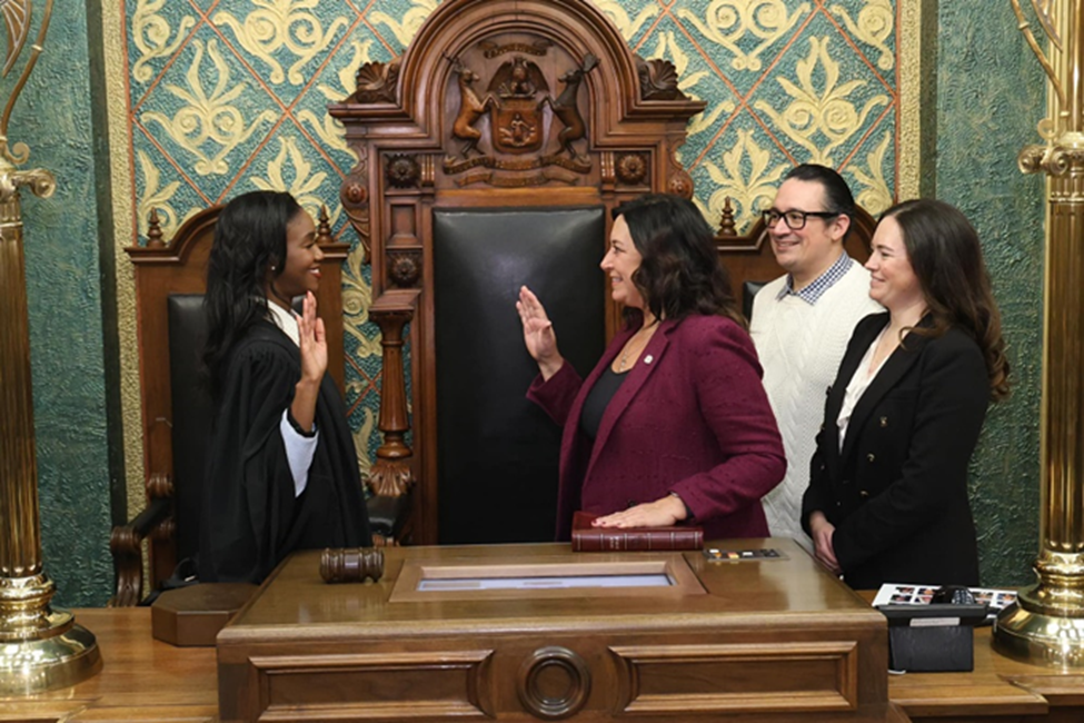 Michigan State Representative Angela Witwer standing with guests while being sworn into the 103rd Legislature by Michigan Supreme Court Justice Kyra Harris Bolden.