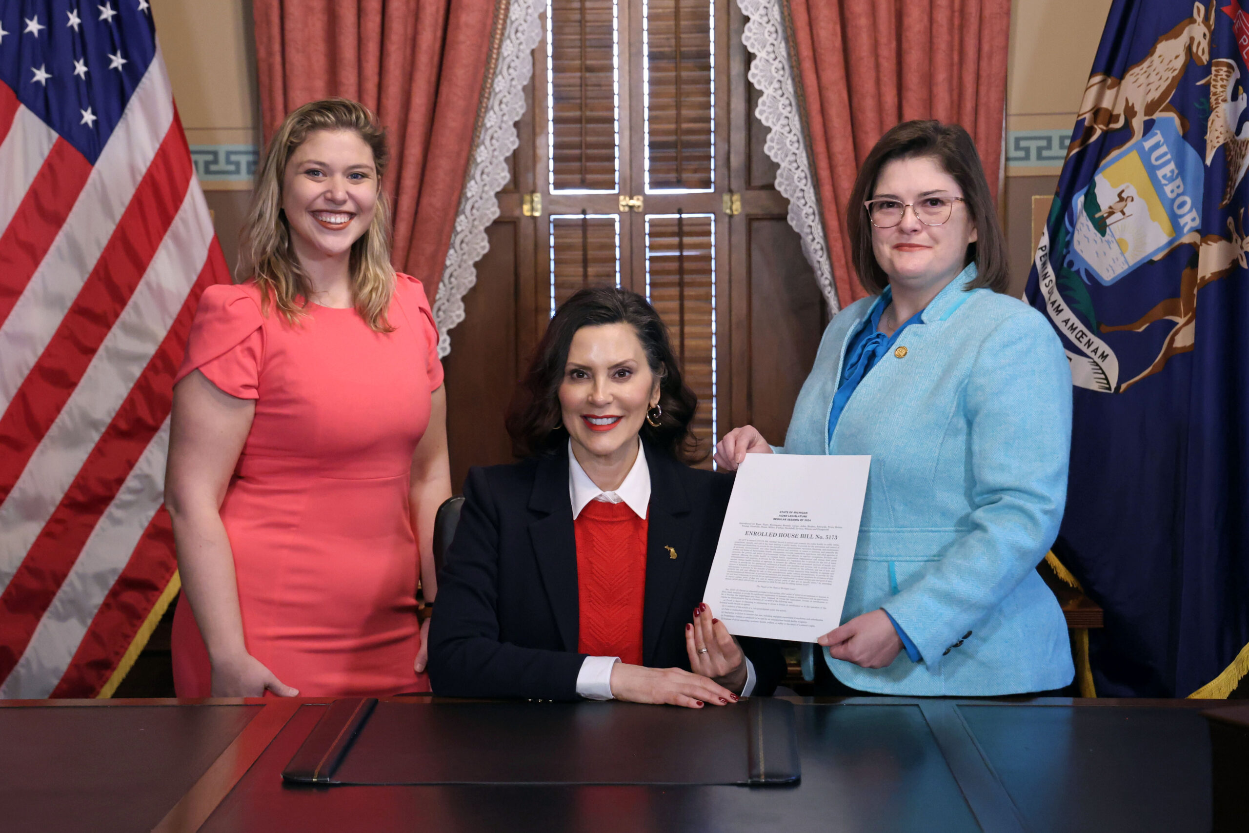 Michigan State Representative Kara Hope holds her maternal health bill, recently signed into law with Michigan Governor Gretchen Whitmer and her legislative director Angie Goulet.