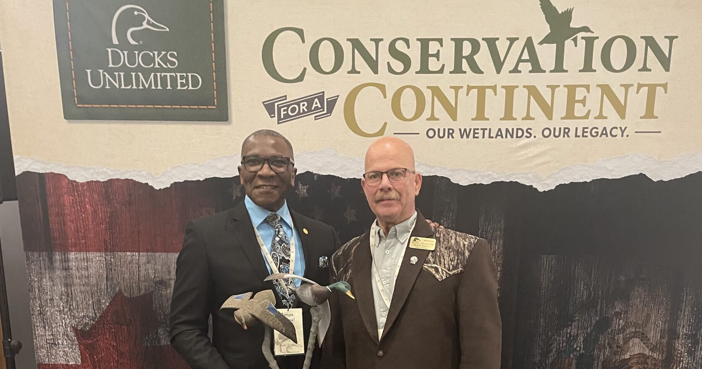 Michigan State Representative Amos O'Neal stands smiling with a Ducks unlimited representative.