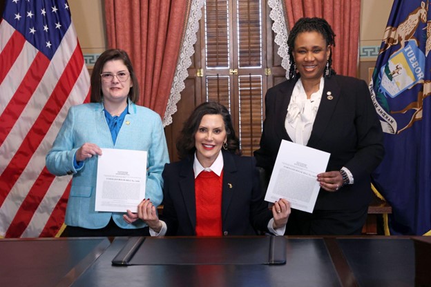 Michigan State Representatives Kara Hope and Stephanie A. Young hold their bills with Michigan Governor Gretchen Whitmer.