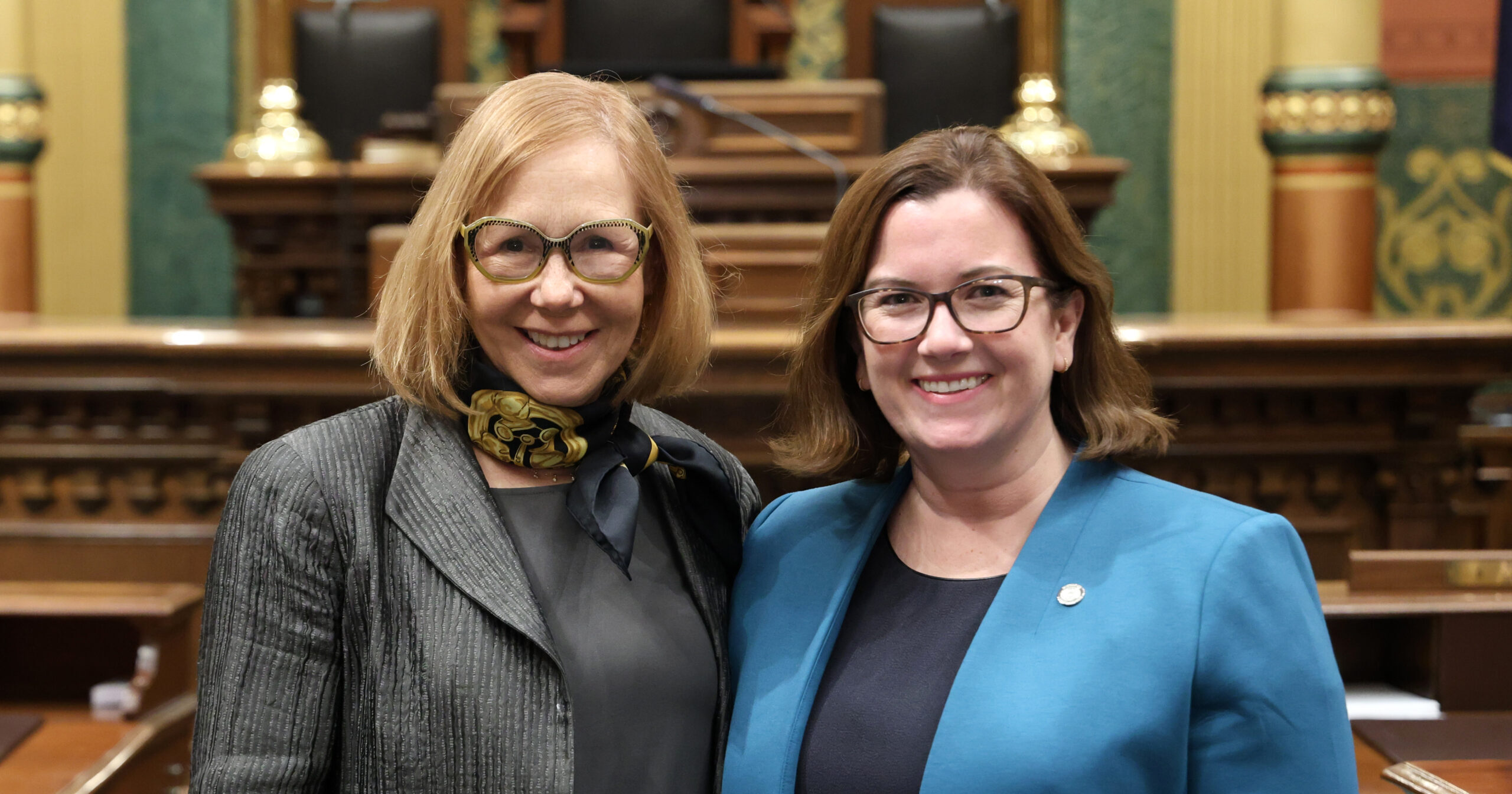 Michigan State Representative Natalie Price standing with Laura Berman, board member of the Michigan League of Conservation Voters, on the House floor.