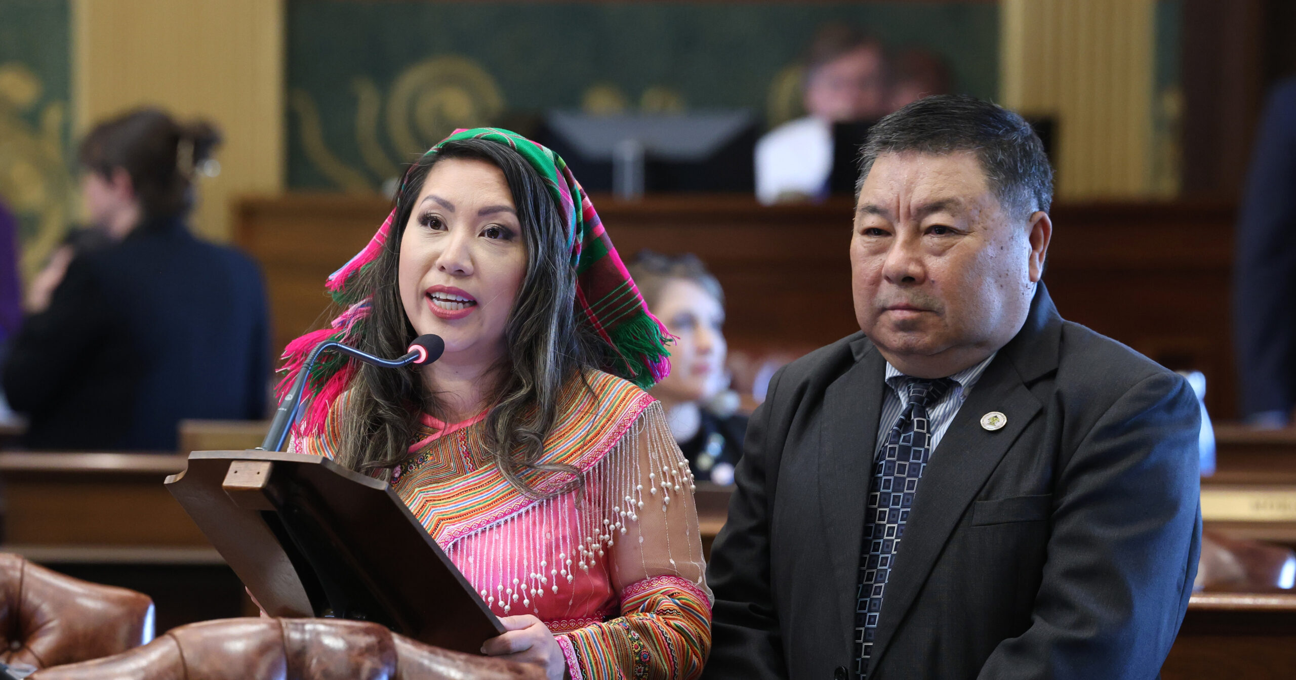 Michigan state Representative Mai Xiong speaking on the House floor next to Chong Cher Xiong.