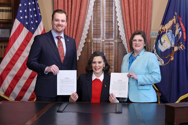 Democratic Floor Leader Fitzgerald and state Representative Kara Hope standing with Michigan Governor Gretchen Whitmer while holding newly signed bills.