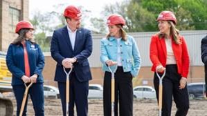 Michigan state Representative Carol Glanville standing with colleagues wearing hard hats and carrying shovels.