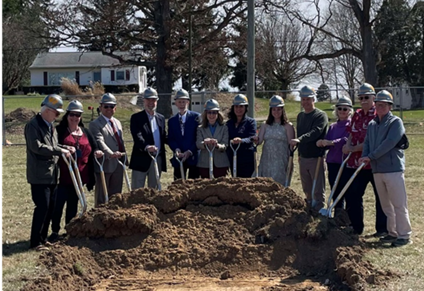 Michigan State Representative Angela Witwer standing Eaton Rapids Teen Space staff members with hardhats and shovels while digging into a pile of dirt.