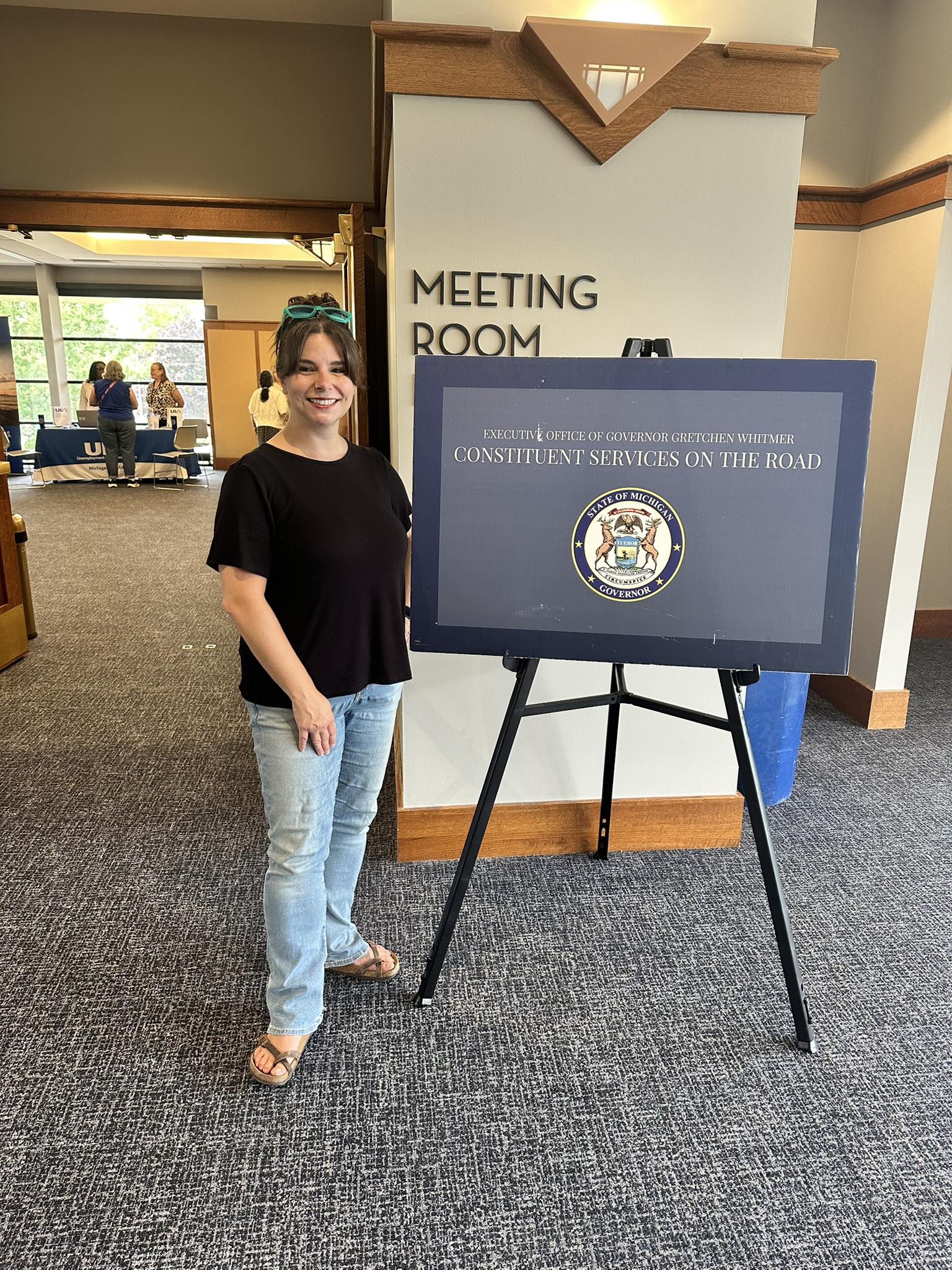 State Rep. Laurie Pohutsky poses next to a poster board at the governor's on the road series of community conversations
