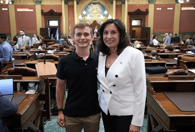 Michigan state Representative Angela Witwer smiling for a photo with Evan Schaefer on the House floor.